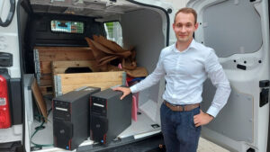 Mann steht vor einem Transporter und legt die Hand auf einen Computer
