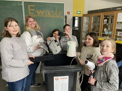 Schülerinnen und Schüler des Krupp-Gymnasiums stehen um eine Sammeltonne und präsentieren Elektroschrott